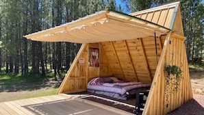 Una pequeña cabaña de madera con techo inclinado y un porche cubierto.
