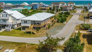 Un quartier résidentiel situé sur la côte, avec des maisons dotées de balcons et de terrasses en bois, une route sinueuse qui traverse le quartier, et l’océan en toile de fond.