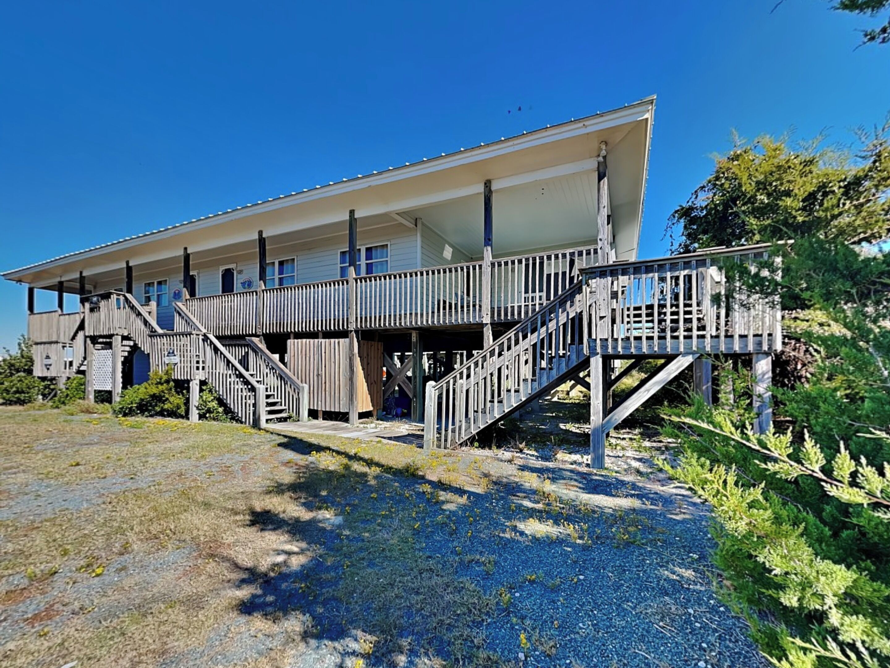 A two-story building with a wooden deck and stairs leading to the entrance.