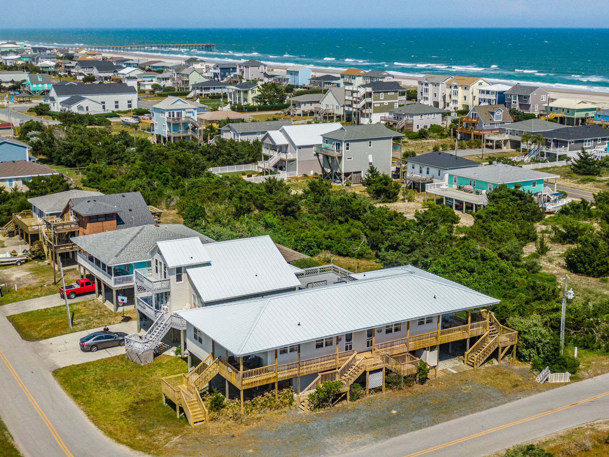 A coastal residential area with houses, a beach, and a pier.