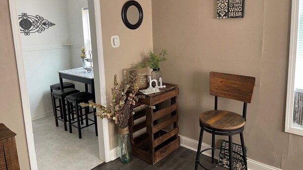 A room with a wooden chair, a small table with decorative items, a mirror, and a wall with a motivational quote.