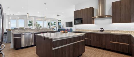 A modern kitchen with dark wood cabinets, stainless steel appliances, and a large island.