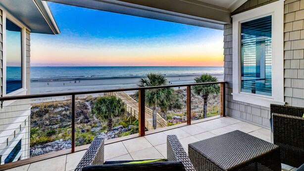 A balcony with a view of the beach and ocean during sunset. - Newly Built 7-bedroom Oceanfront Stunner with private pool. (Hilton Head Island)