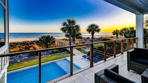 A balcony with a view of the beach and ocean at sunset. - Newly Built 7-bedroom Oceanfront Stunner with private pool. (Hilton Head Island)
