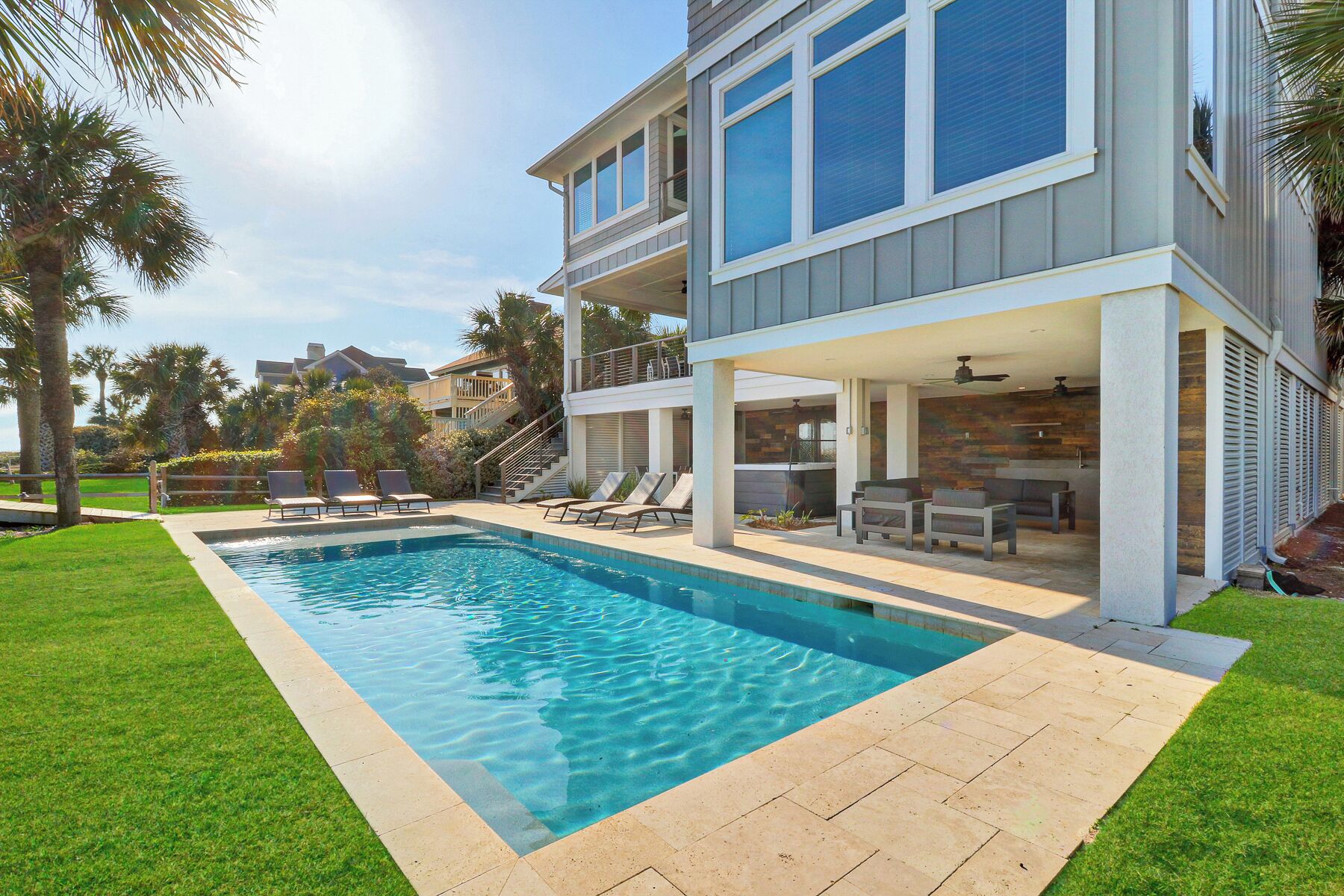 Ein modernes, zweistöckiges Haus mit Pool, Sitzgelegenheit im Freien und einer überdachten Terrasse.