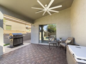 Une terrasse équipée d’un barbecue, d’un coin salon et d’un ventilateur de plafond.