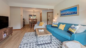A living room with a blue sofa, wooden coffee table, and a TV on a wooden stand. - Updated Condo Near Mountain, Free Shuttle, Pool, Hot Tub! (Steamboat Springs)