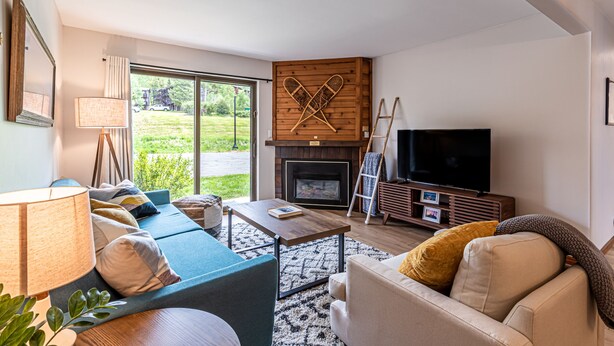 A living room with a sofa set, a coffee table, a fireplace, a television, and a view of the outdoors. - Updated Condo Near Mountain, Free Shuttle, Pool, Hot Tub! (Steamboat Springs)