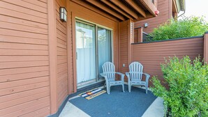 A wooden exterior with a sliding glass door, two Adirondack chairs, and a welcome mat. - Updated Condo Near Mountain, Free Shuttle, Pool, Hot Tub! (Steamboat Springs)
