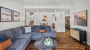 A modern living room with a grey sectional sofa, a marble coffee table, and a staircase leading to an upper level. - Renovated 3-Bedroom Condo at Timber Run – Spacious Mountain Retreat with Prime L (Steamboat Springs)
