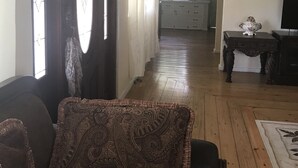 A hallway with a patterned rug, a sofa, and a television on a stand. - Beautiful, tranquil Home. 8 minutes from the International Airport (Vieux Fort)