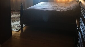 A bedroom with a large bed, a wooden floor, and a view through a window with curtains. - Beautiful, tranquil Home. 8 minutes from the International Airport (Vieux Fort)