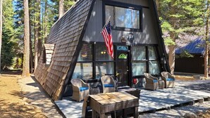 A cabin with a sloped roof, a porch with wicker furniture, and an American flag.