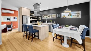 A modern kitchen with a central island, built-in appliances, and a dining area with a white tablecloth.
