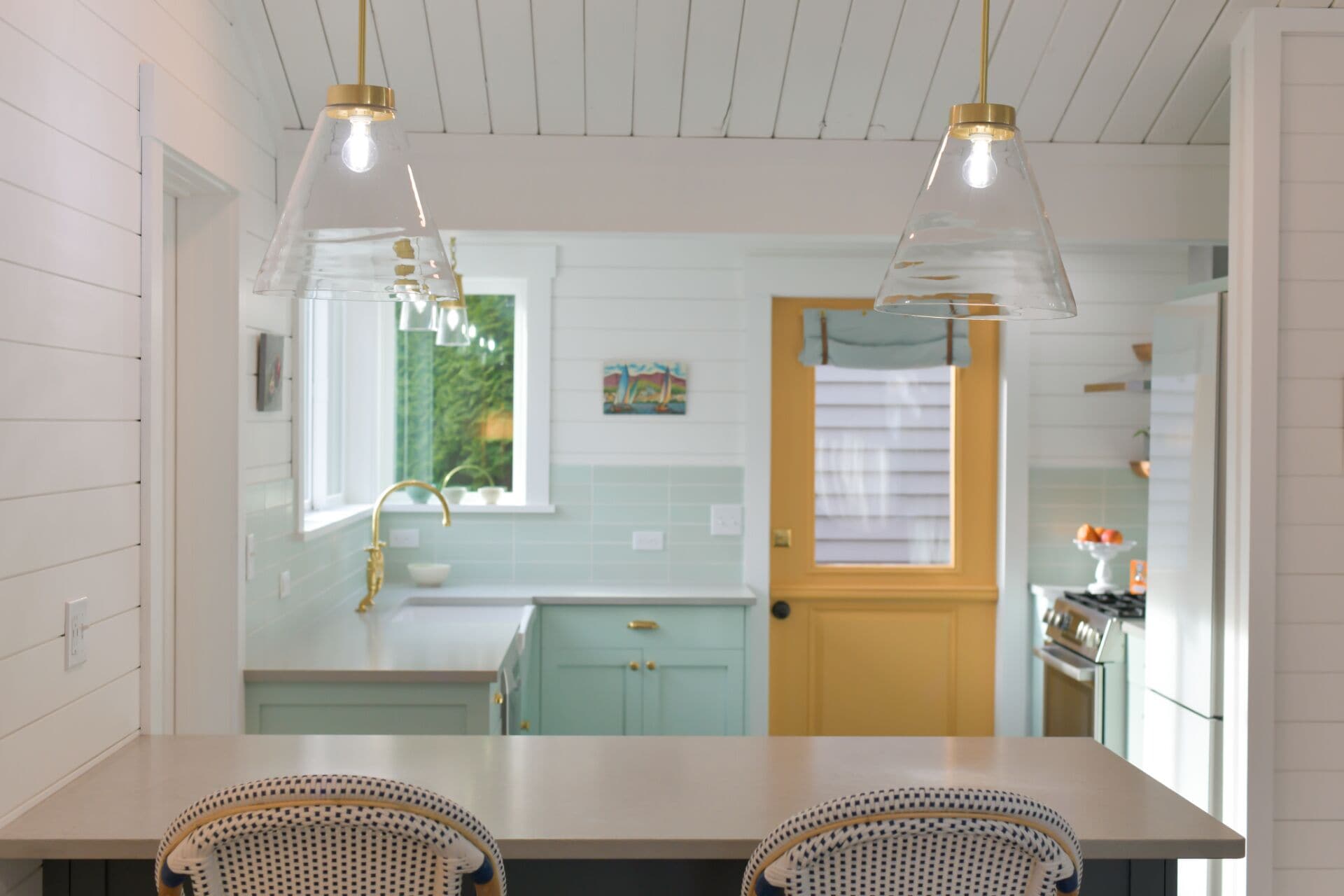 A kitchen with white cabinetry, a window, and a door.