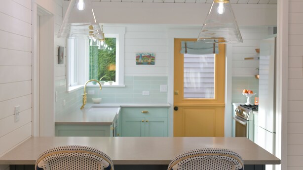 Una cocina con muebles blancos, una ventana y una puerta.