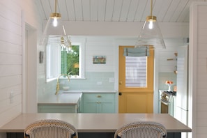Una cocina con muebles blancos, una ventana y una puerta.