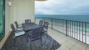 A balcony with a table and chairs, a patterned rug, and a view of the ocean. - The Gulf Is Calling –Lazy River Getaway Phoenix West 1204 (Orange Beach)