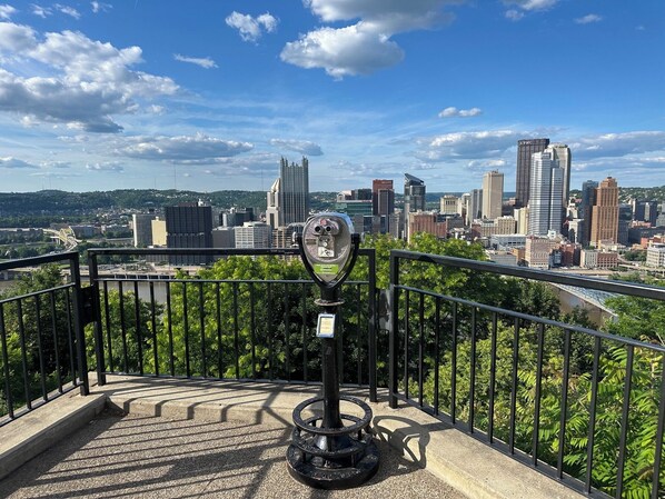 Un paisaje urbano que muestra edificios altos, un telescopio y una barandilla.