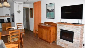 Een woonkamer met een open haard, houten meubels, een flatscreen televisie en een ingelijste foto aan de muur.