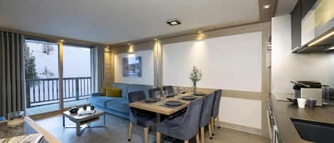Une cuisine moderne avec un coin repas, un canapé et une vue sur un paysage enneigé.