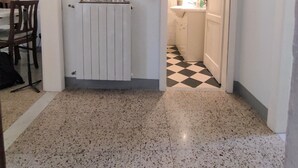 Un passadís amb un radiador, una porta que dona a un bany i un terra de pissos.