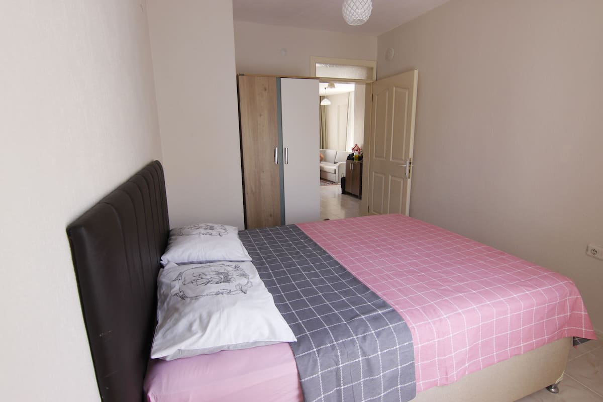 A bedroom with a bed, a wardrobe, and a door leading to another room.
