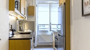 A modern kitchen with wooden cabinets, stainless steel appliances, and a window providing natural light.