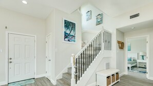 A staircase with a white handrail and black balusters, leading to a bedroom with a bed and a nightstand. - 2nd row Gulf Views w/ Large Deck, Open Living, Private Bedrooms - Cool & Coastal (Galveston)