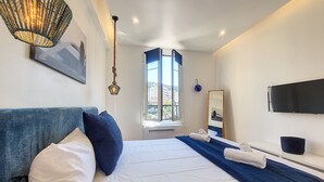 A modern hotel room with a large bed, a flat-screen TV, a window with a view, and a ceiling light fixture. - N&J - L'ANCRE - Port district - Close Old Town (Niza)