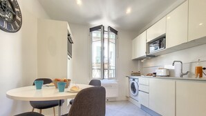 A compact kitchen with a dining area, a washing machine, and a window providing natural light. - N&J - L'ANCRE - Port district - Close Old Town (Niza)