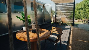 A camper van parked on a deck with a round wooden table, chairs, and a lantern. -  Bab Al Nojoum Al Mugheirah (Al Mirfa)