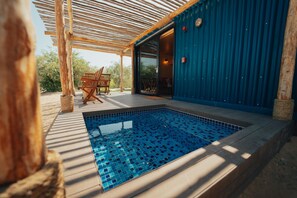 A swimming pool with a tiled deck, wooden chairs, and a covered area with a pergola. -  Bab Al Nojoum Al Mugheirah (Al Mirfa)