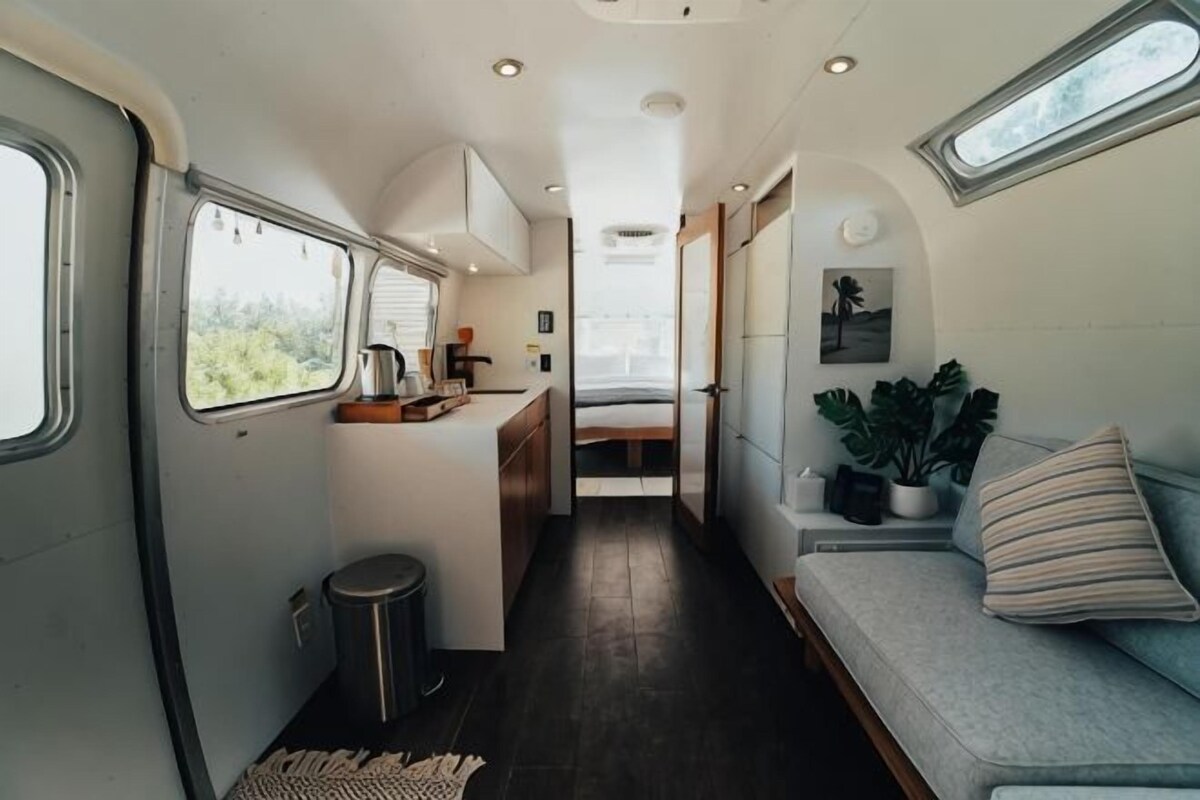 A compact RV interior with a kitchenette, a seating area, and a small window.