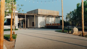 A modern building with a covered entrance, wooden columns, and a sign reading "BABALNOJUM". -  Bab Al Nojoum Al Mugheirah (Al Mirfa)
