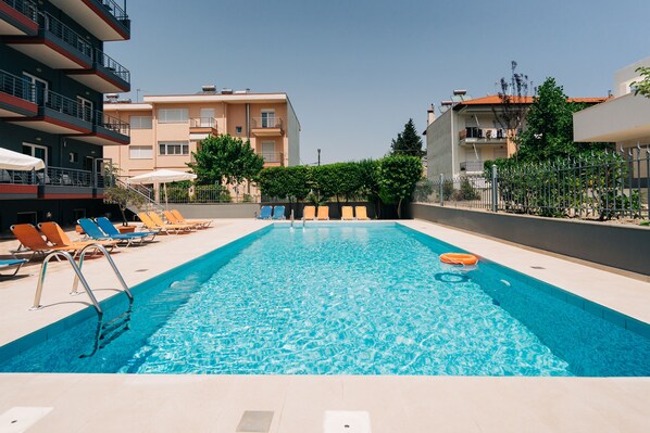 En säsongsöppen utomhuspool, parasoller och solstolar