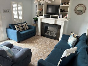 A living room with a fireplace, a television, and a blue sofa.