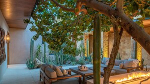 A cozy outdoor seating area with a fire feature, surrounded by cacti and a tree. - Luxury Ocean View Villa w/ Heated Pool, Hot Tub & Steps to Beach in Ritz Complex (San Jose Del Cabo)