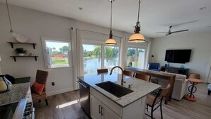 A modern kitchen with a central island, pendant lighting, and a view of the outdoors.