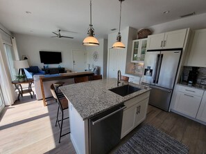 A modern kitchen with a central island, stainless steel appliances, and pendant lighting.