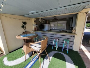 An outdoor patio with a round table and chairs, a bar area, and a small stool. - Indian Bayou Lake House 1 - Lakeside Oasis (Fort Myers Beach)
