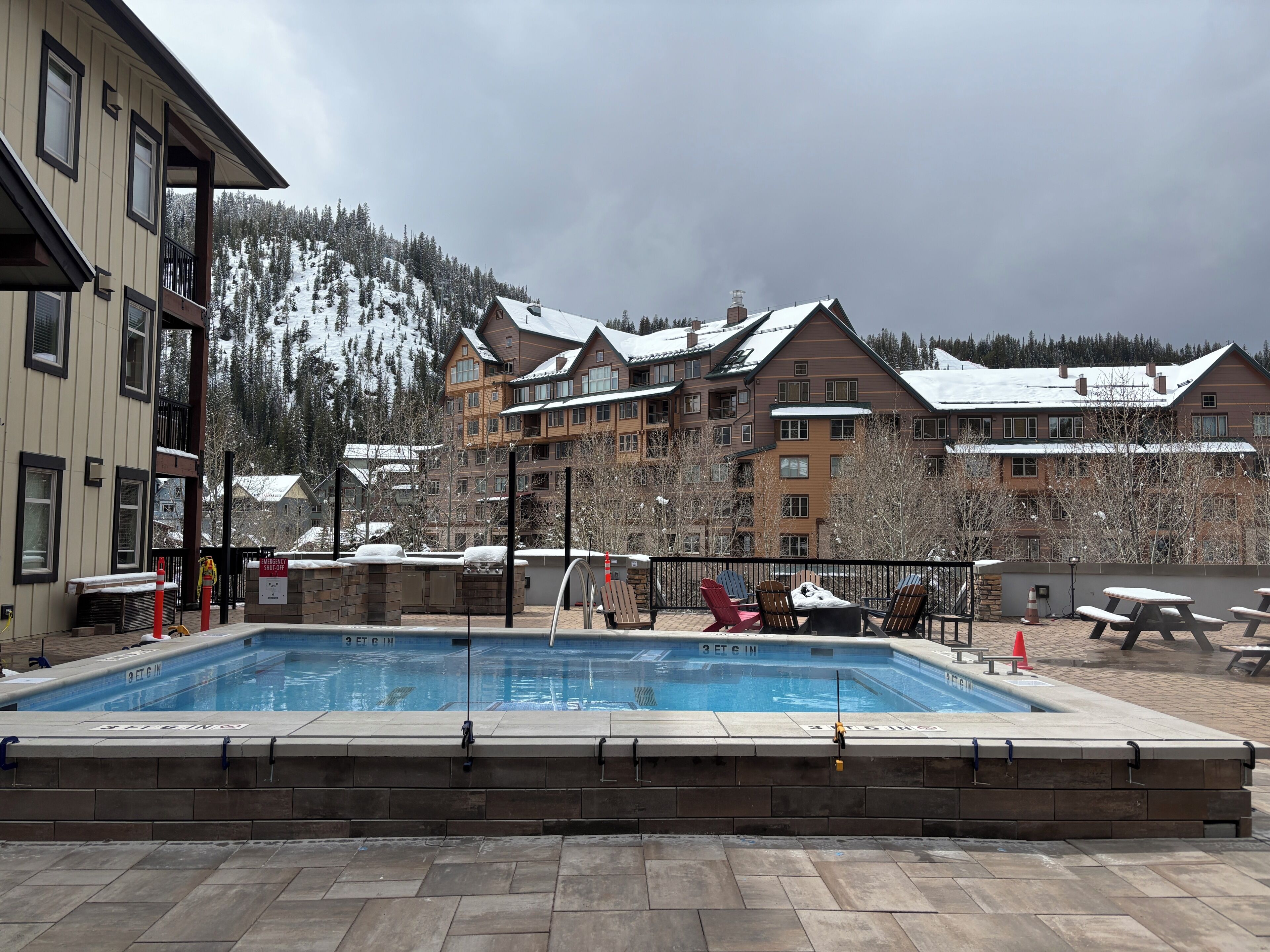 A swimming pool with a 3 ft 6 in depth, surrounded by lounge chairs and a building with multiple balconies.