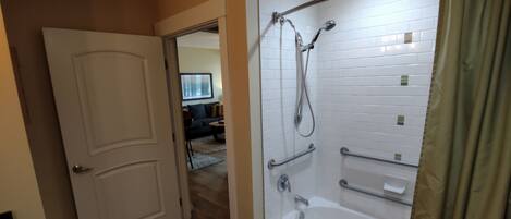 Un baño con ducha a nivel, barras de apoyo y bañera.