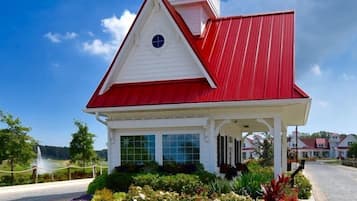 Charming single-story building with a distinctive red roof and a small tower on the roof, surrounded by a well-maintained garden.