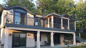 A modern two-story house with a covered porch, large windows, and a stone facade.