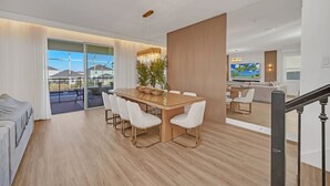 A modern living room with a dining area, large windows, and a view of the outdoors.