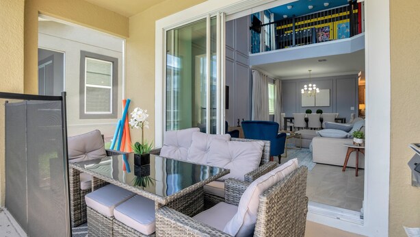 A spacious balcony with wicker furniture, a glass table, and a view of the interior.