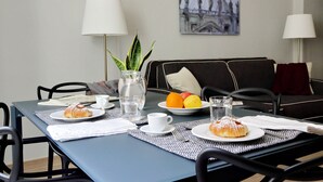 A dining table set with plates of food, glasses of water, and a vase with a plant. - Monti Apartments - M5 (Rome)