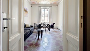 A hallway with a dining area, a sofa, and a table with chairs.