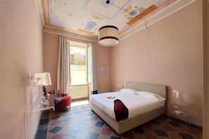 A hotel room with a bed, a nightstand, a lamp, a chair, and a view of the outside.